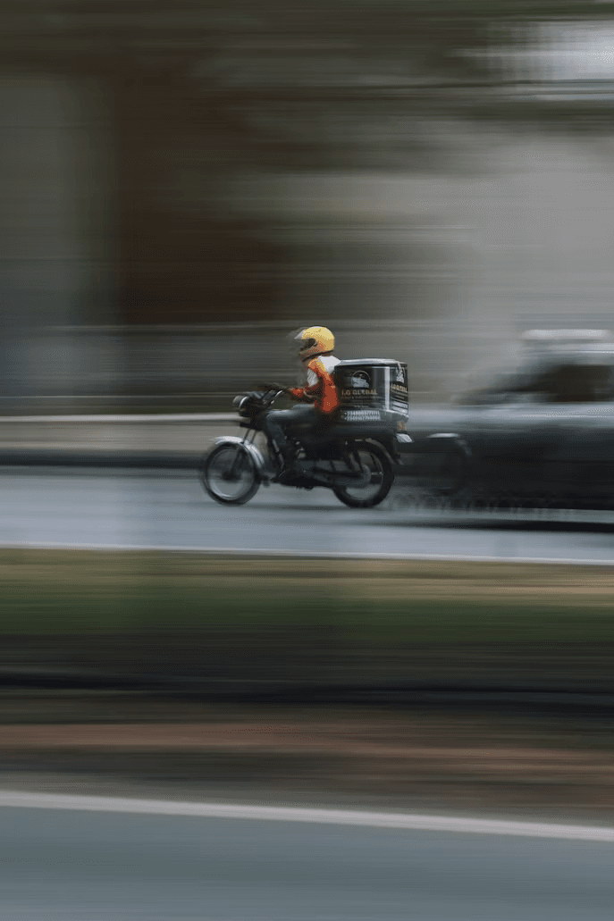 Delivery motorcyclist speeding through city traffic